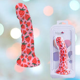 A Maia Juci Strawberry Themed Suction Dong 7" by Maia Toys, featuring a sturdy silicone design with a vibrant strawberry pattern and suction cup base, is pictured next to its packaging. The background is adorned with soft, multicolored bokeh lights.